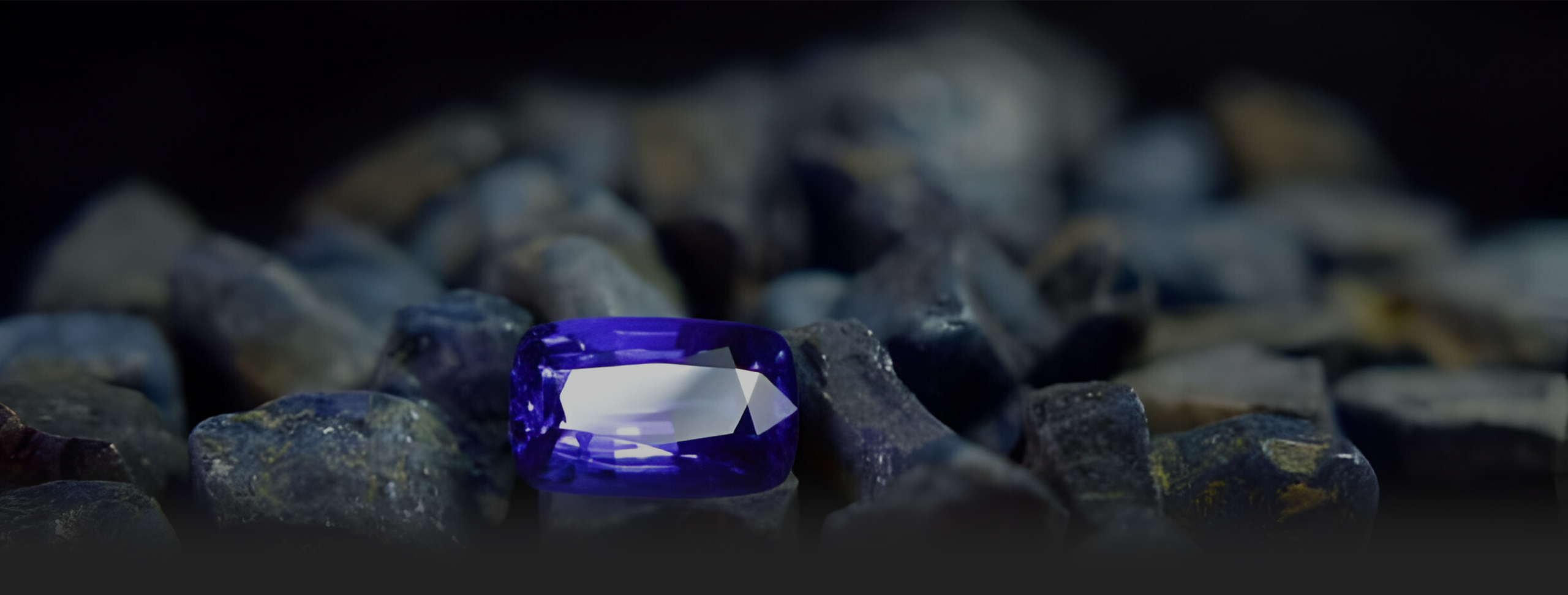 A vivid blue sapphire surrounded by natural rough gemstones